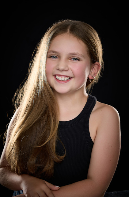Portrait of Olivia smiling under a warm stage spotlight